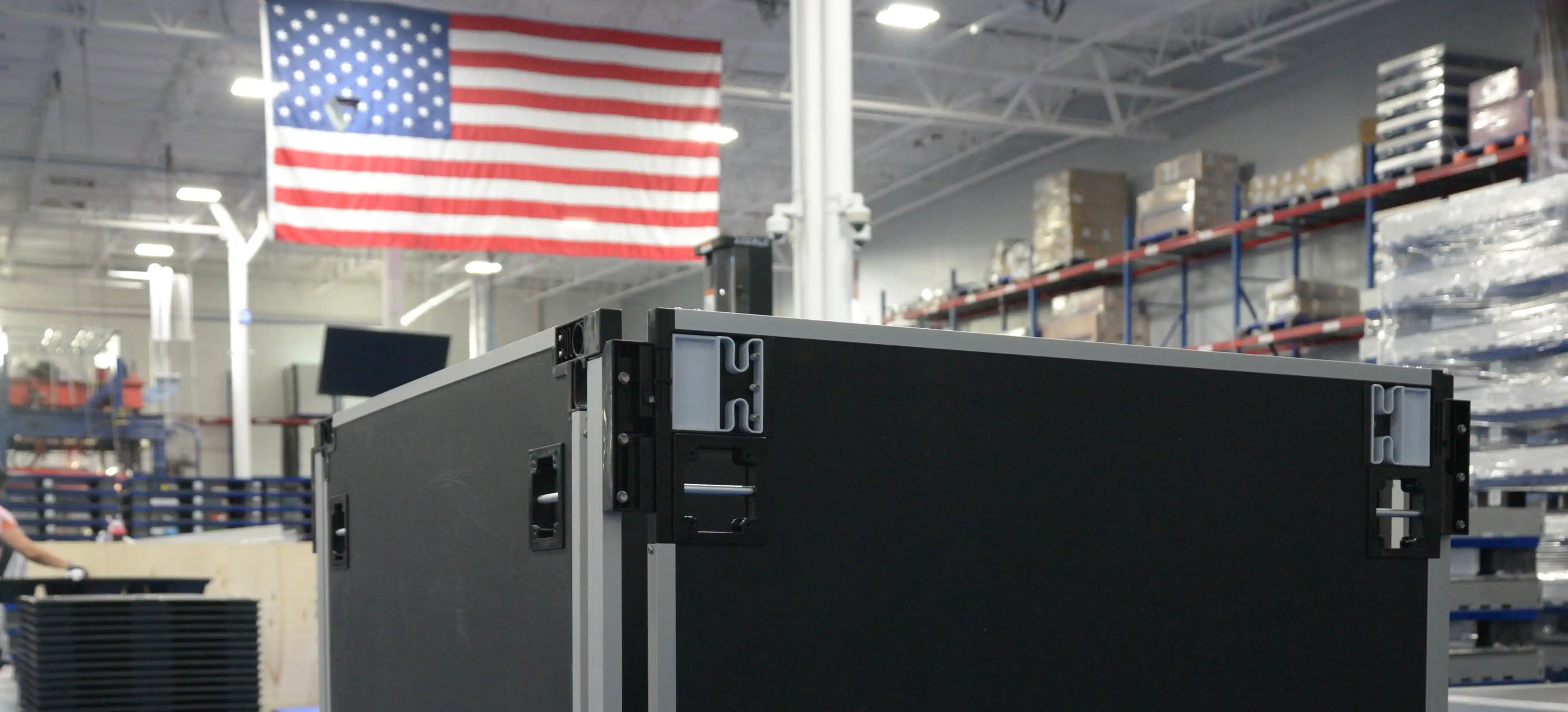 Collapsible container with American flag in the background in a warehouse setting.