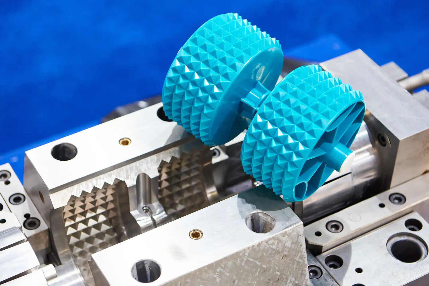 Turquoise injection molded gears on a metal machine with a blue background