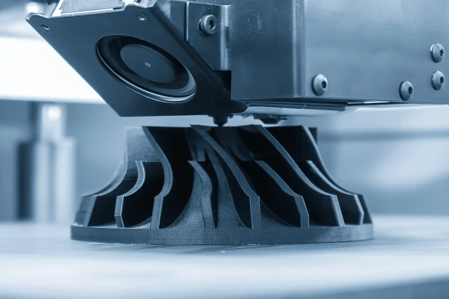 3D printer in action with a black plastic object being printed.