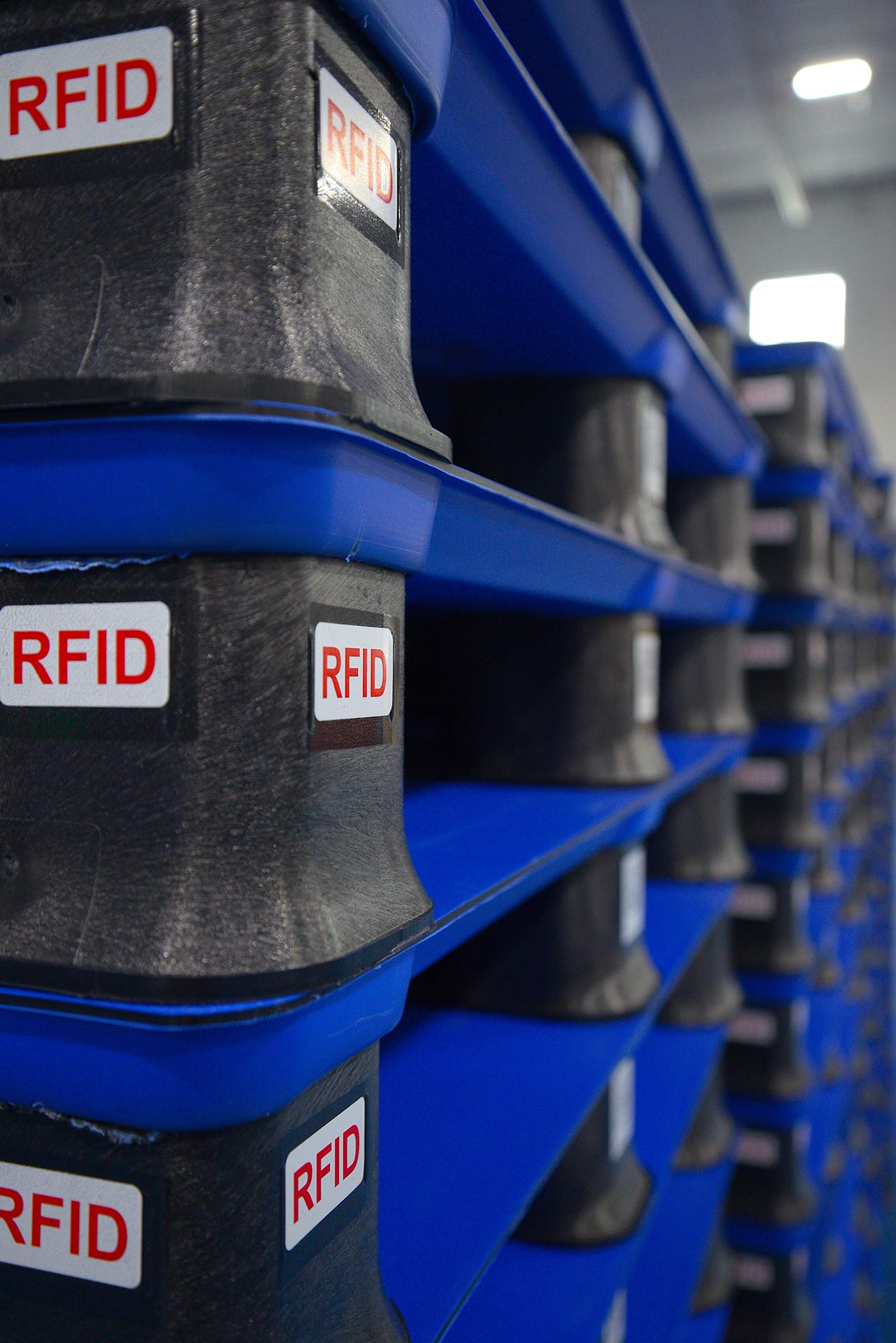 Stacks of blue pallets with RFID labels in a warehouse setting