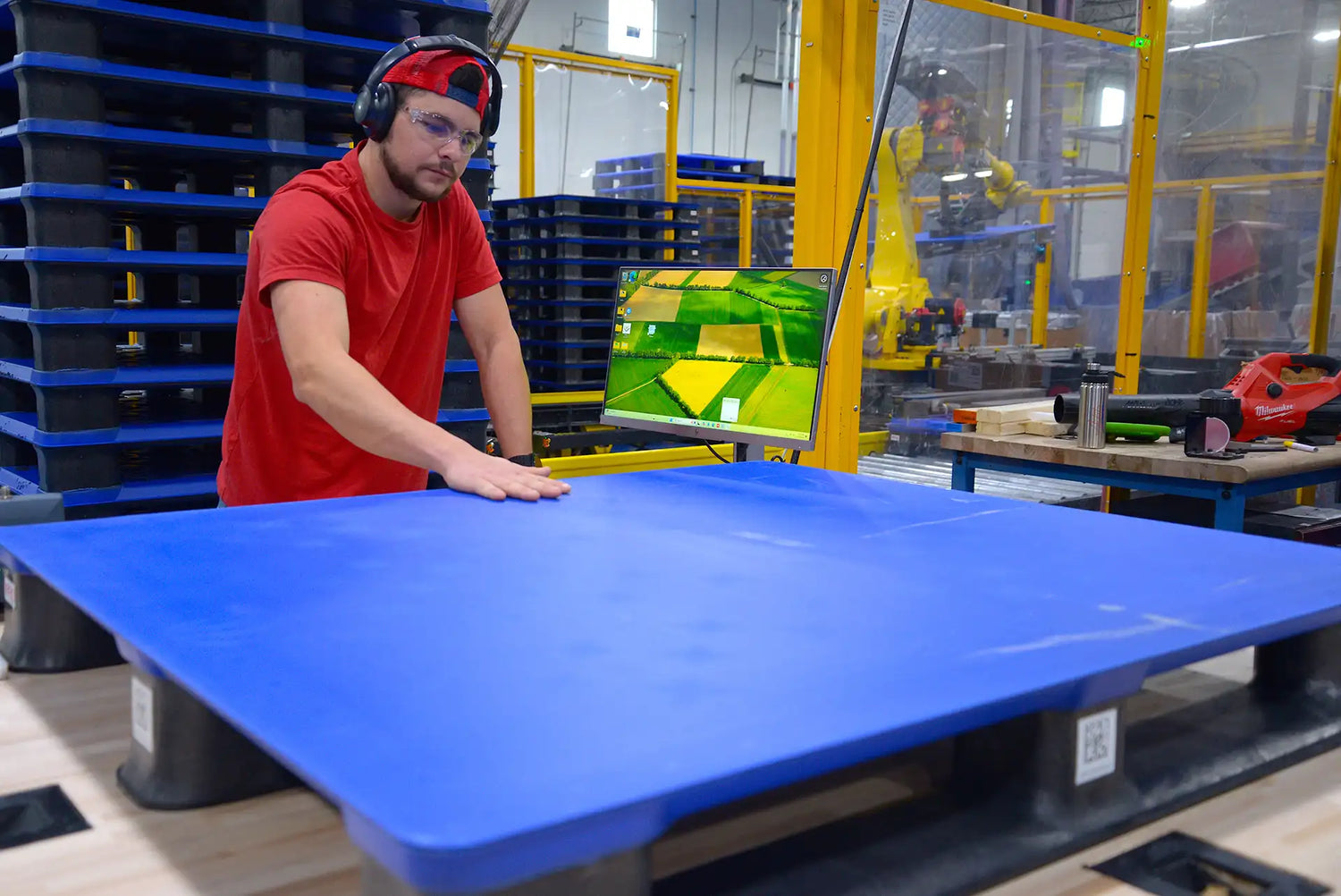 Person in a red shirt working with a blue pallet in an industrial setting