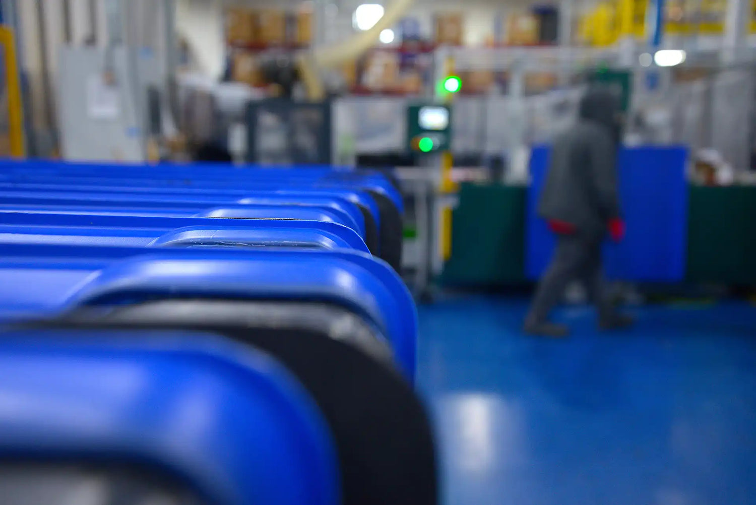 Factory floor with blue machines and a person in the background